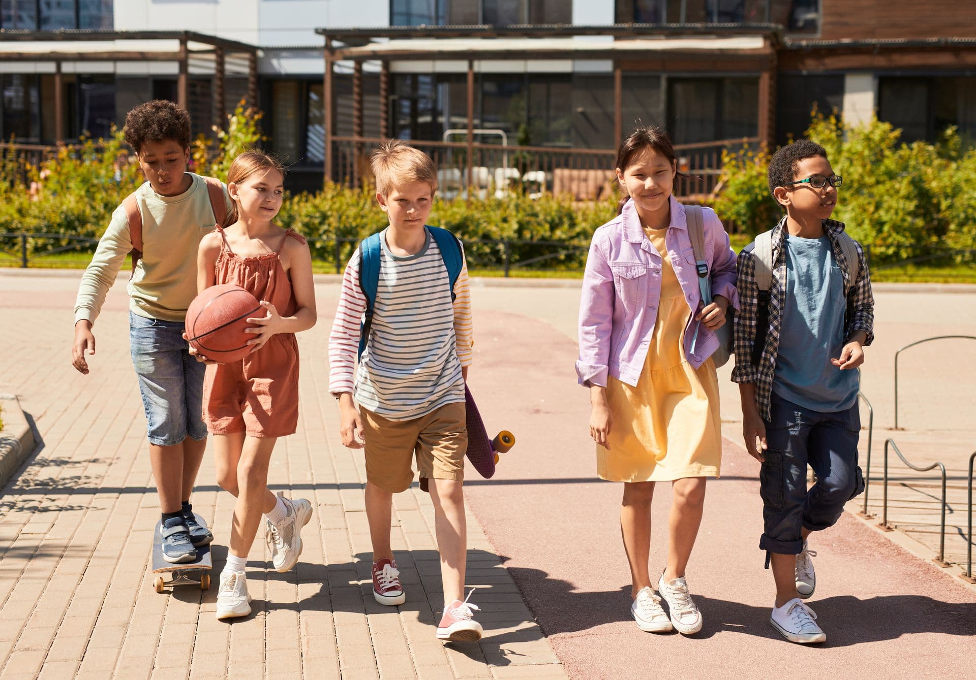 Kids wearing backpacks walking together along the sidewalk on their way to school