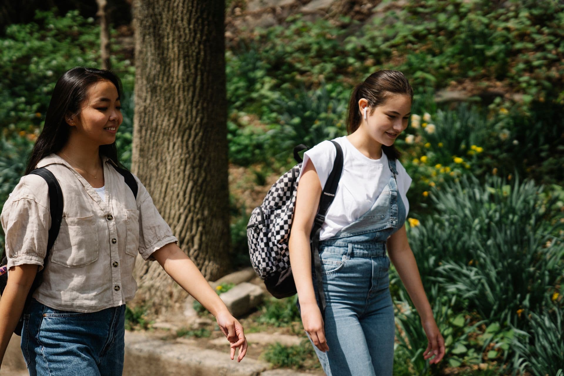Three teenage friends walking together and chatting on a sidewalk